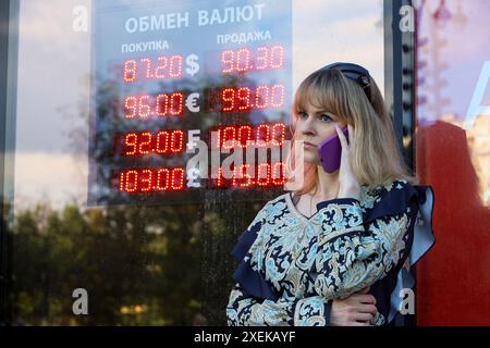 Mädchen, das auf dem Handy spricht, steht in der Nähe der Wechselstube auf der Stadtstraße, Preise des russischen Rubels, US-Dollar, Euro Stockfoto