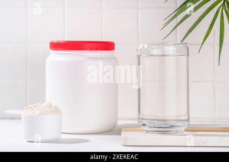 Kollagenproteinpulver mit Glas Wasser auf weißem Küchentisch. Natürliche Ergänzung für Schönheit, Gesundheit der Haut, Knochen, Gelenke und Darm, Anti Stockfoto