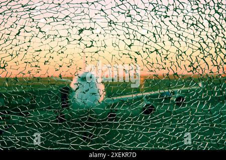 Weißes Flugzeug im Flughafen hinter dem zerbrochenen Triplex-Glas mit vielen Rissen. Abstrakte Hintergründe für den Transport Stockfoto