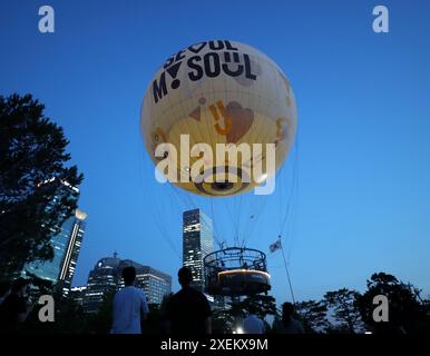 Seoul, Südkorea. Juni 2024. Touristen schauen sich den SEOUL DAL Ballon in Seoul, Südkorea, 28. Juni 2024 an. Am Freitag wurde ein mondförmiger Heliumballon namens SEOUL DAL im Yeouido Park in Seoul gestartet. Touristen können eine Fahrt mit dem Ballon machen, um einen Blick auf die Stadt von oben zu genießen. Quelle: Yao Qilin/Xinhua/Alamy Live News Stockfoto