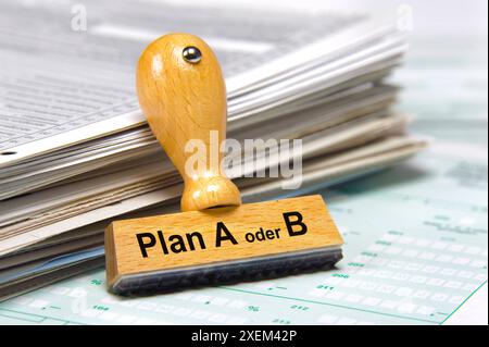 Plan A oder B an einem Stapel mit Papier lehnt ein Holzstempel mit dem Aufdruck Plan A oder B *** Plan A oder B A Holzstempel mit dem Aufdruck Plan A Stockfoto