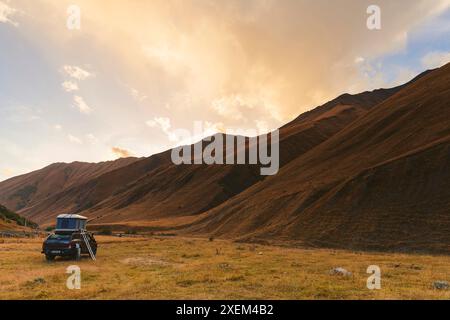 Sportfahrzeug mit Zeltstruktur auf dem Dach, das im Kazbegi-Nationalpark, Mzcheta-Mtianeti, Georgia, geparkt ist Stockfoto