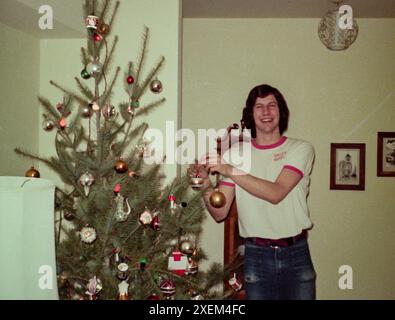 Teenager Son hilft, den Weihnachtsbaum der Familie in einem Vorstadthaus in Santa Rosa, Kalifornien, 1970er Jahre, USA zu schmücken Stockfoto