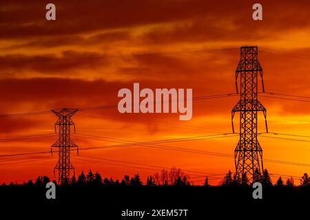 Silhouette großer elektrischer Türme aus Metall mit einem farbenfrohen, dramatischen Himmel im Hintergrund; Calgary, Alberta, Kanada Stockfoto