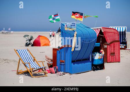 Borkum, Deutschland. Juni 2024. Bei sonnigem Wetter steht am Strand der Insel eine Liege mit verschiedenen Flaggen. Quelle: Hauke-Christian Dittrich/dpa/Alamy Live News Stockfoto