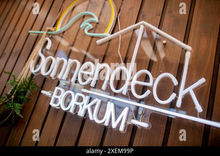 Borkum, Deutschland. Juni 2024. Das Logo von Milchbude Sonnendeck hängt an einer Holzwand der Strandbar. Milchstände haben auf der Nordseeinsel Borkum eine lange Tradition. Quelle: Hauke-Christian Dittrich/dpa/Alamy Live News Stockfoto
