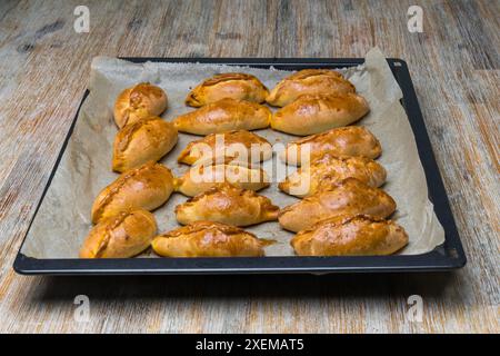 Mini Pirozhki oder Piroshki auf einem Kochtablett. Hausgemachte gebackene Hefe in Form eines Bootes mit Kohlfüllungen. Essen in Osteuropa. Stockfoto