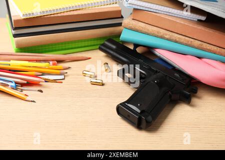 Pistole, Kugeln und Schulpapier auf Holztisch Stockfoto