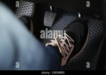 Mann in Turnschuhen drückt auf das Pedal der Autobremse, Nahaufnahme Stockfoto