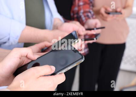 Leute, die Smartphones mit leeren Bildschirmen in Innenräumen halten, Nahaufnahme Stockfoto