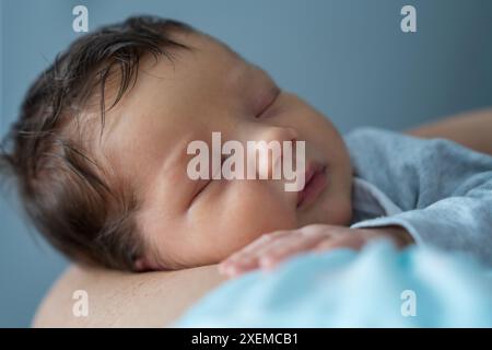 Mom hält einen neugeborenen Jungen, das Baby schläft süß. Mutter Hände und Baby Nahaufnahme. Säuglingsgesundheit und -Entwicklung. Die Geburt eines Kindes und die Liebe o Stockfoto