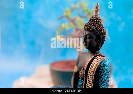 Ein Nahfoto einer Buddha-Statue mit einem sanften, ruhigen Ausdruck vor einem beruhigenden hellblauen Hintergrund. Stockfoto