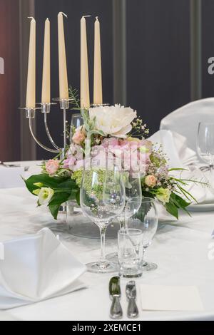 Hochzeitsdekoration. Servierter Hochzeitstisch mit dekorativen Naturblumen und. Details zu Feiertagen. Blumenarrangements, Teller und Kerzen in Kerzenleuchtern Stockfoto