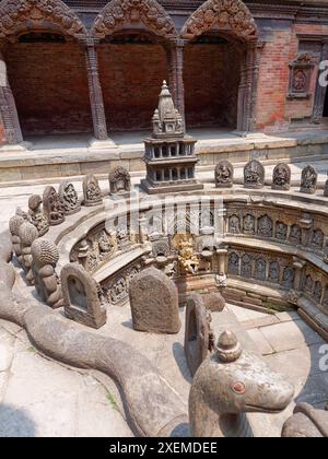 Die komplizierten Steinschnitzereien und eine goldene Statue in einem alten Tempel in Nepal. Vertikale Aufnahmen unter der glühenden Sonne. Stockfoto