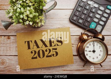 Steuern 2025 Typografie-Text mit Rechner auf hölzernem Hintergrund Stockfoto