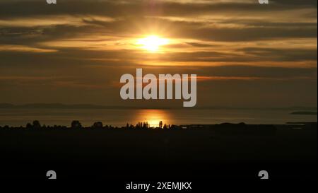 Sonnenuntergang auf der Insel Rügen mit Blick auf den großen Jasmund Bodden. Bewölkt, trüb und daher verschleiert, aber sehr schön und romantisch. Stockfoto