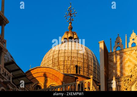 Nahaufnahme einer Kuppel des Markusdoms (Basilika di San Marco) und des Dogenpalastes auf der Dachterrasse, die das warme Sonnenlicht reflektiert; Venedig, Venetien, Italien Stockfoto