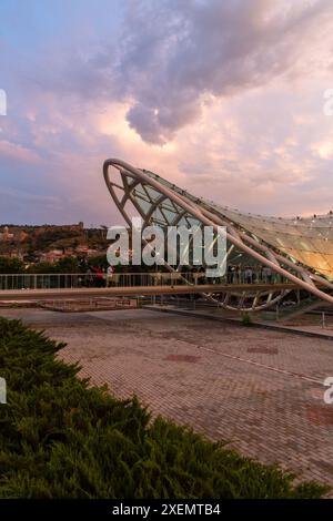 Tiflis, Georgien – 16. Juni 2024: Die Friedensbrücke ist eine bogenförmige Fußgängerbrücke, eine Stahl-Glas-Konstruktion über den Fluss Kura, die die Brücke verbindet Stockfoto