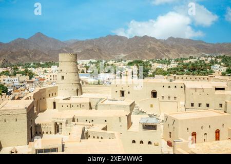 Bahla Zitadelle Festung Innenhof und runder Turm mit Stadt im Hintergrund, Bahla, Oman Stockfoto