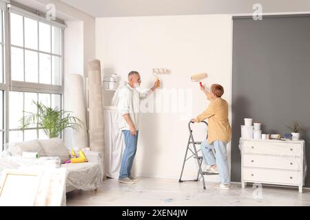 Reifes Ehepaar, das die Wand während der Reparatur in ihrem neuen Haus anstrich Stockfoto