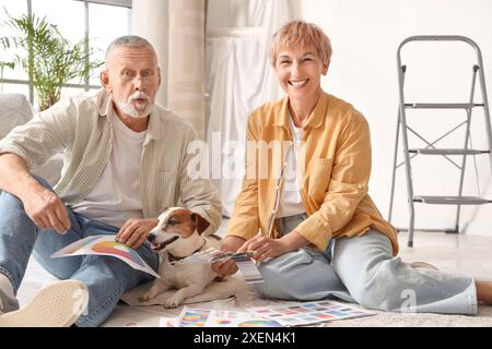 Reifes Paar mit Farbpaletten und Hund während der Reparatur in ihrem neuen Haus Stockfoto