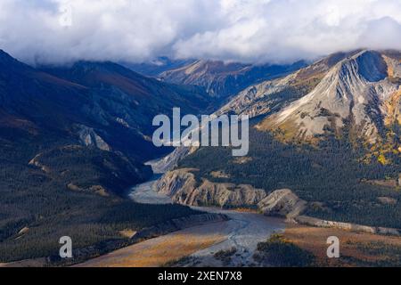 Aus der Vogelperspektive des Canada Creek, der aus den Bergen des Kluane National Park fließt, mit niedrigen Wolken über den Gipfeln, während sich der Herbst langsam mit dem... Stockfoto