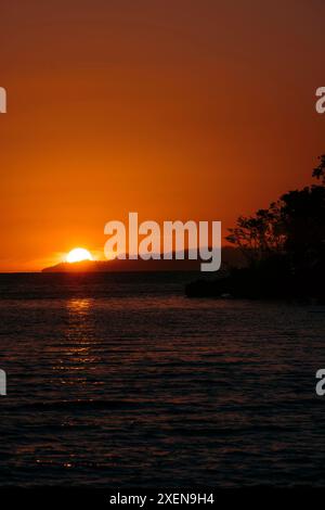 Dramatisch glühender Sonnenuntergang und roter Himmel aus einem Resort auf Bolilanga Island auf den Tongean Inseln Indonesiens Stockfoto