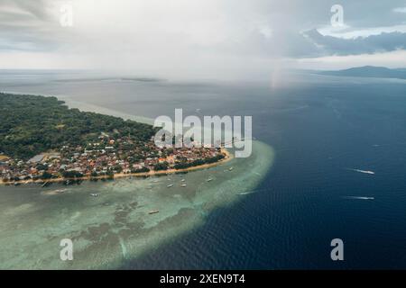 Luftaufnahme der Stadt Bunaken mit Regenfällen aus Wolken in der Ferne über der Celebessee in Nord-Sulawesi, Indonesien Stockfoto