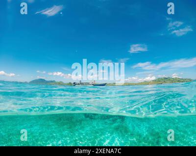 Geteilter Blick auf das klare türkisfarbene Meer und das touristische Tauchboot entlang der Küste im Kepulauan Togean Nationalpark Stockfoto