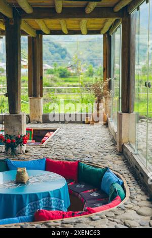 Versenkte Sitzbereiche mit bunten Kissen in einem Raum mit Glaswänden für natürliches Licht; Ngoc Chien, Muong La District, Son La, Vietnam Stockfoto