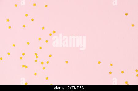 Goldene Sterne glitzern Konfetti auf hellrosa Hintergrund. Festliche Feiertage. Minimales Konzept. Flache Lagen. Stockfoto
