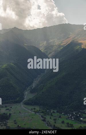 Der Fluss verläuft durch eine Schlucht entlang bewaldeter Berghänge des Kaukasus-Gebirges, wobei das Sonnenlicht die Wolken darüber beleuchtet Stockfoto