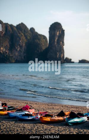 Kajaks in einer Reihe am Ao Nang Beach mit blauem Meer und zerklüfteten Klippen entlang der Küste, Krabi, Thailand; Krabi, Thailand Stockfoto