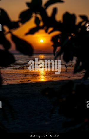 Goldene Sonne, die in den Himmel sinkt und sich im Wasser in Richtung Ao Nang Strand in Thailand spiegelt; Krabi, Thailand Stockfoto