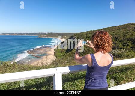 Eine Frau macht mit ihrem Smartphone ein Foto von Burwood Beach in Newcastle Australien. Die Region Newcastle ist die Heimat einer fantastischen Küste. Stockfoto