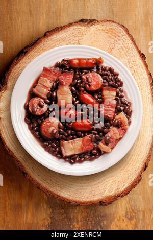 brasilianische Feijoada in Keramikschale isoliert auf rustikalem hölzernem Hintergrund. Kopierbereich. Draufsicht Stockfoto