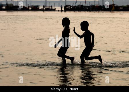 Kinder kühlen sich in Sangam (Zusammenfluss der Flüsse Ganges, Yamuna und mythischen Saraswati) an heißen Sommertagen in Prayagraj, Indien. Stockfoto