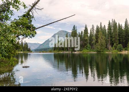 Ein horizontales Foto des Lake Wenatchee im Bundesstaat Washington, umgeben von immergrünen Bäumen und Cascade Mountains, die sich im ruhigen Seewasser spiegeln. Stockfoto