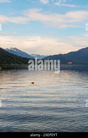 Vertikales Foto des Lake Wenatchee, Washington, mit Gipfeln der Kaskadenkette in der Ferne und weißen Wolken in einem blassblauen Himmel. Stockfoto