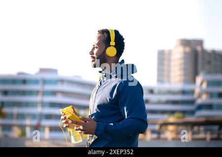 Runner man mit Smartphone und Sportflasche Wasser in den Händen draußen. Stockfoto