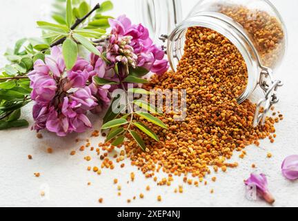 Gesunde Bienenpollenkörner. Bienenpollen auf einem Glas und Akazienblüten Stockfoto