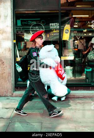 Eine Frau läuft mit einem roten Piratenhut und einem sehr großen Teddybären Stockfoto