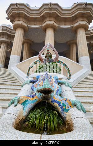 Salamander-Skulptur (auch bekannt als „DRAC“ oder „Drache“) mit Hypostyle-Halle im Hintergrund. Park Güell von Antonio Gaudí. Barcelona. Katalonien. Spanien. Stockfoto