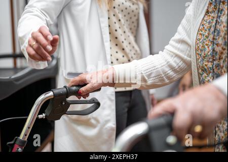 Krankenschwester hilft der alten Frau, im Pflegeheim mit Walker zu laufen. Junge Krankenschwester hilft älteren Patienten mit einem Gehgestell, um im Krankenhauskorridor zu gehen. Hochwertige Fotografie Stockfoto