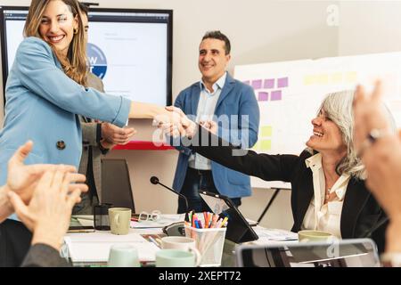 Professionelles Geschäftsgebrauch in einem Meeting. Team feiert erfolgreiche Zusammenarbeit und Einigung. Büroumgebung mit zufriedenen Profis. Stockfoto