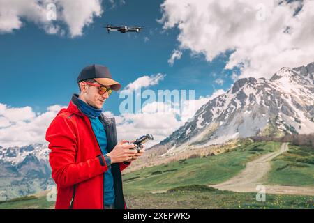 Eine Person, die eine Drohne bedient, mit der die Luftkamera über majestätische Berge fliegt und atemberaubende Naturaufnahmen von oben macht. Stockfoto