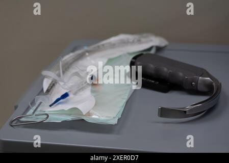 Nahaufnahme medizinischer Intubationsgeräte, einschließlich eines Laryngoskops, einer Spritze und anderer Werkzeuge, die in einer klinischen Umgebung ordentlich auf einem Tablett platziert werden. Stockfoto