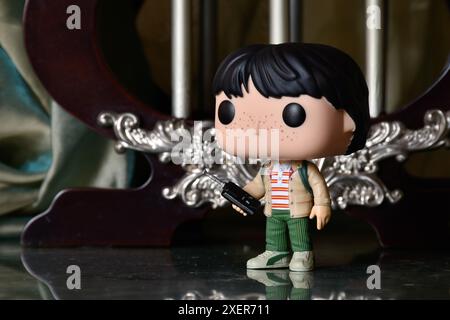 Funko Pop Actionfigur von Mike mit Walkie-Talkie aus der beliebten Horror-TV-Serie Stranger Things. Reflektionsboden, grüner Vorhang, Vintage Palast. Stockfoto