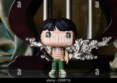 Funko Pop Actionfigur von Mike mit Walkie-Talkie aus der beliebten Horror-TV-Serie Stranger Things. Reflektionsboden, grüner Vorhang, Vintage Palast. Stockfoto