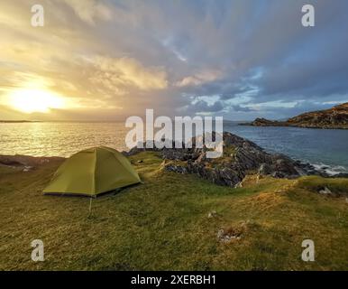 Green Zelt Wildcamping an einer grasbewachsenen und felsigen Küste bei Sonnenuntergang in Smirisary, nahe Glenuig, Westküste Schottlands Stockfoto